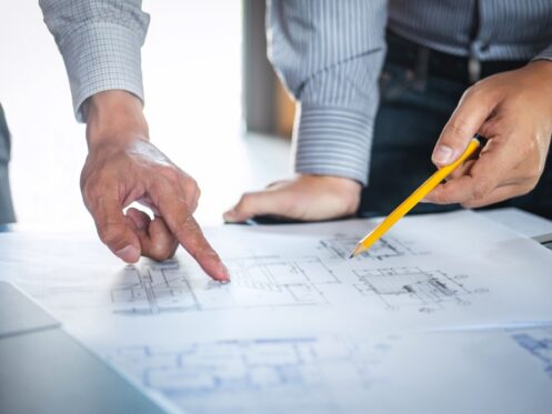 Construction engineering or architect discuss a blueprint while checking information on drawing and sketching, meeting for architectural project of partner.